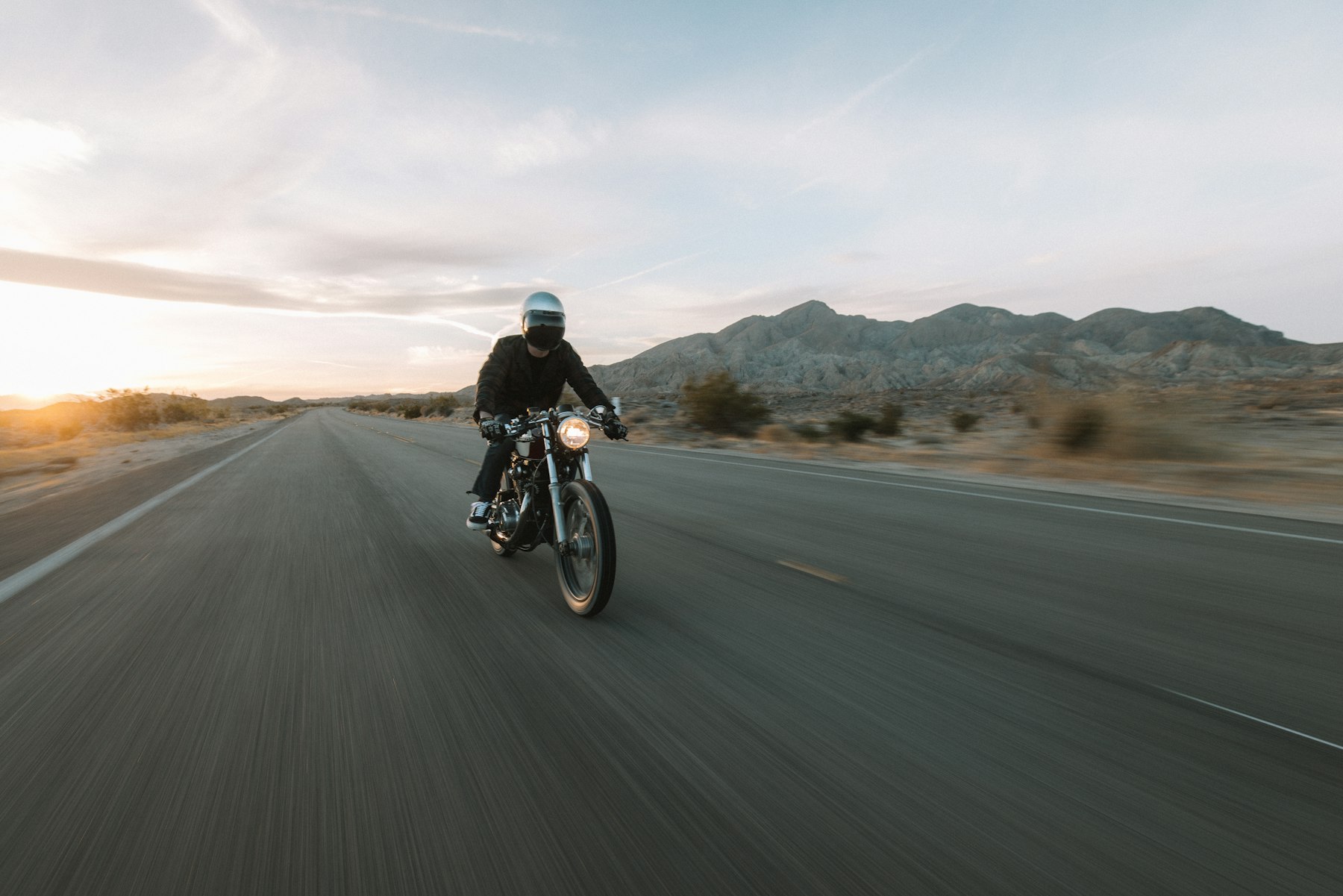Motociclista em uma estrada no deserto ao amanhecer